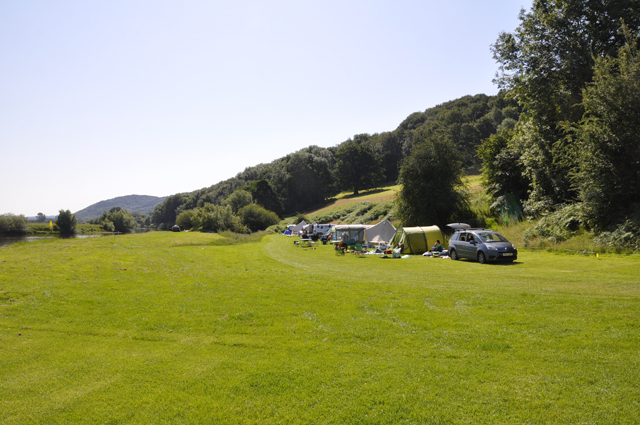 Tents pitched along the riverside camping meadow